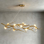 Low angle on this Clérachic gold branch chandelier, its white ceramic blossoms lit warm, against a grey plaster wall and ceiling.