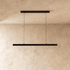 Clérachic black linear pendant, its slim bar catching the light, hangs against a warm plaster wall.
