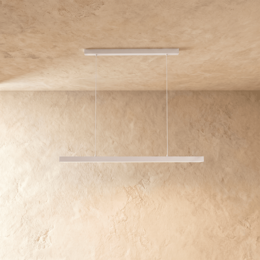 Clérachic white linear pendant light hangs from twin cables against a warm limewash wall and ceiling.