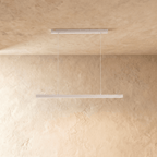 Clérachic white linear pendant light hangs from twin cables against a warm limewash wall and ceiling.