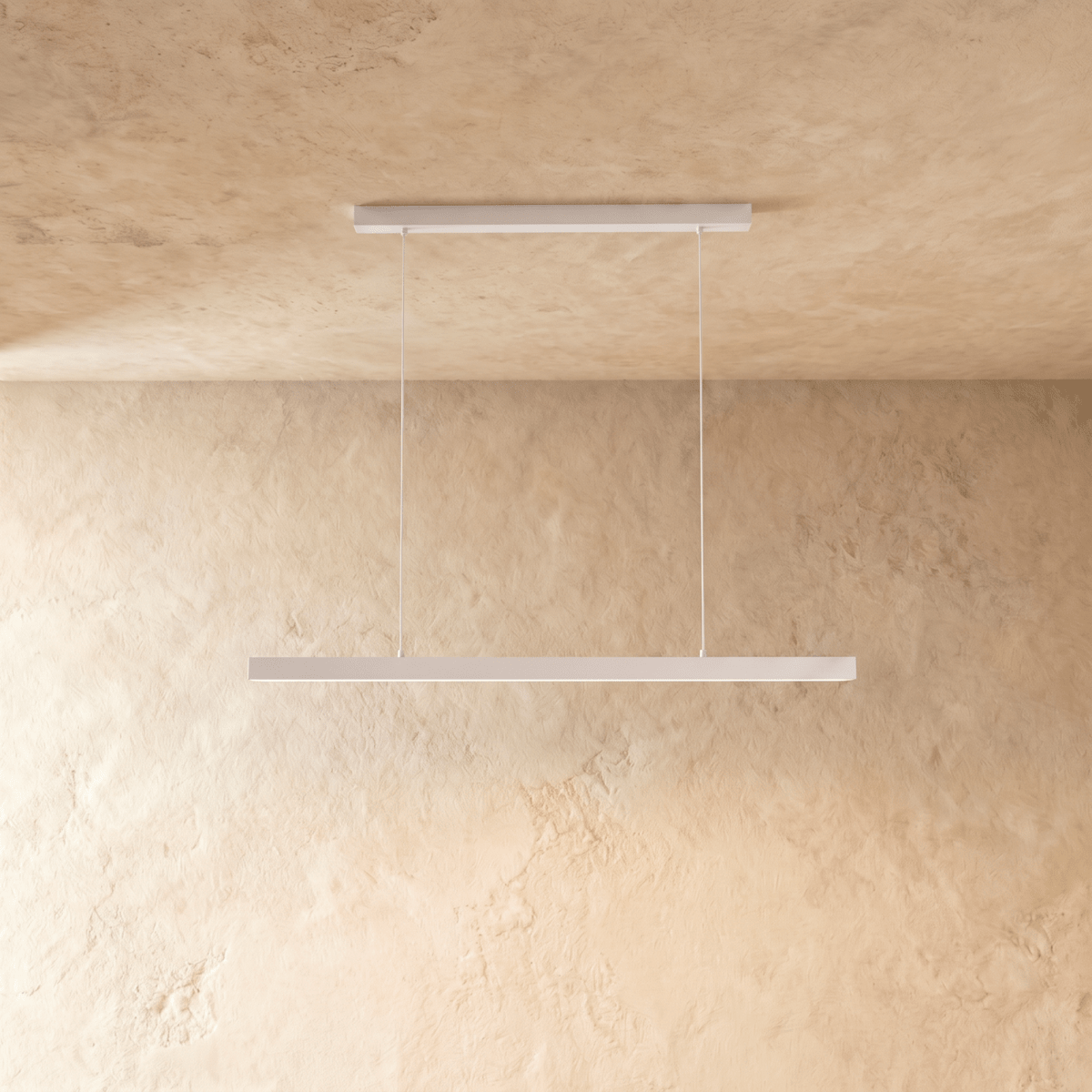 Clérachic white linear pendant light hangs from twin cables against a warm limewash wall and ceiling.