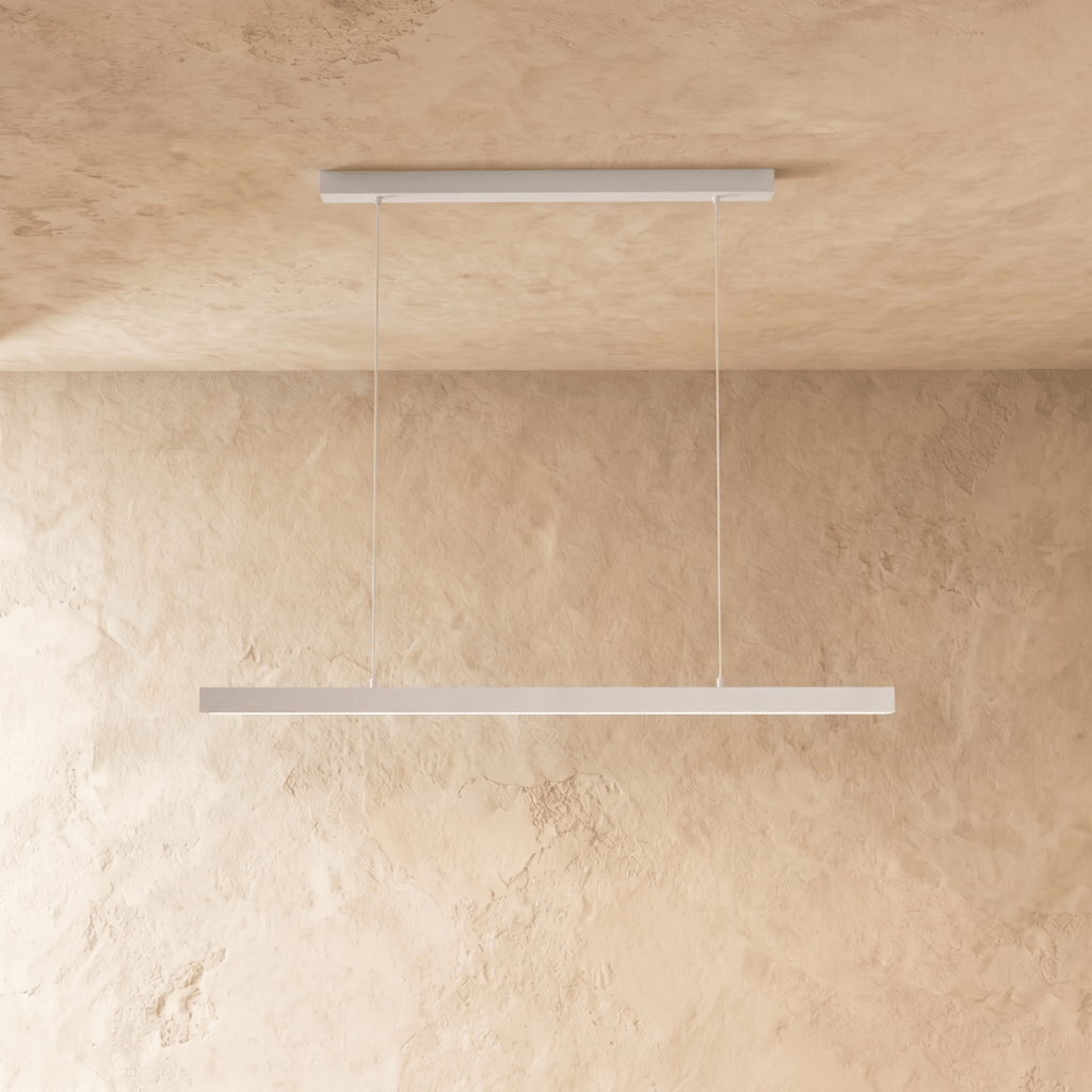 Clérachic white linear pendant light suspended by two thin cables above a sand-toned limewash wall.