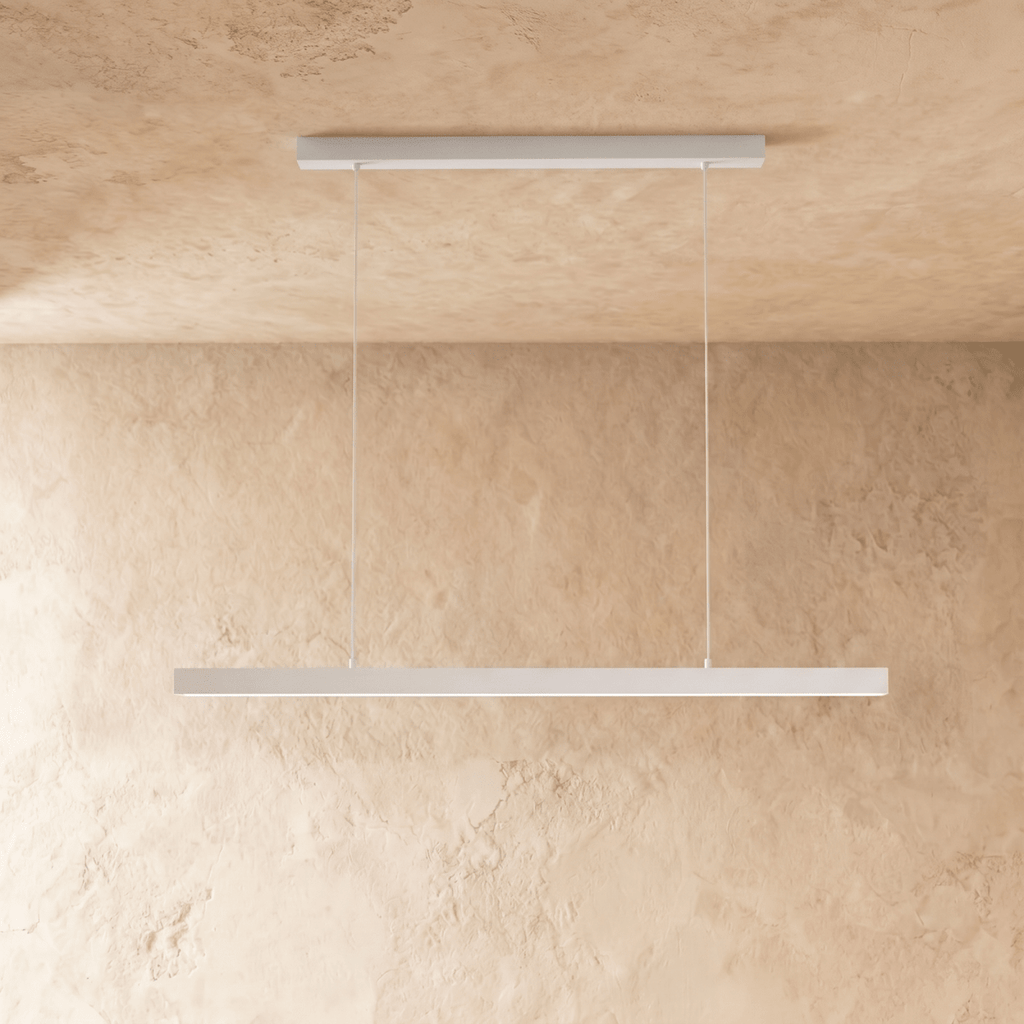 Clérachic white linear pendant, its slim bar catching the light, hangs against a warm plaster wall.
