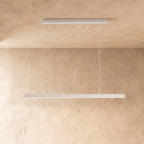 Clérachic white linear pendant bar suspended from a plaster ceiling, shown against a limewash wall.