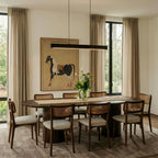 Clérachic black linear pendant lights a walnut dining table, warm curtains and an equestrian print behind.