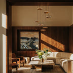 Clérachic gold LED disc pendants on fine cords hanging in a warm timber-panelled living room above a marble coffee table.