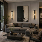 Two black Clérachic loop wall lights lit either side of a large abstract canvas, above a grey sofa and dark coffee table.