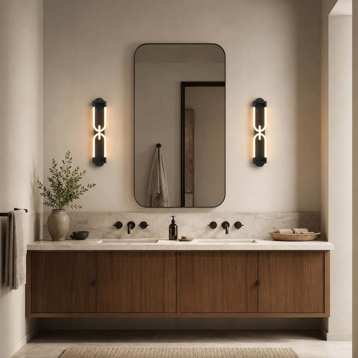 Two black Clérachic wall lights lit either side of a rounded mirror, above a floating walnut vanity with black taps.