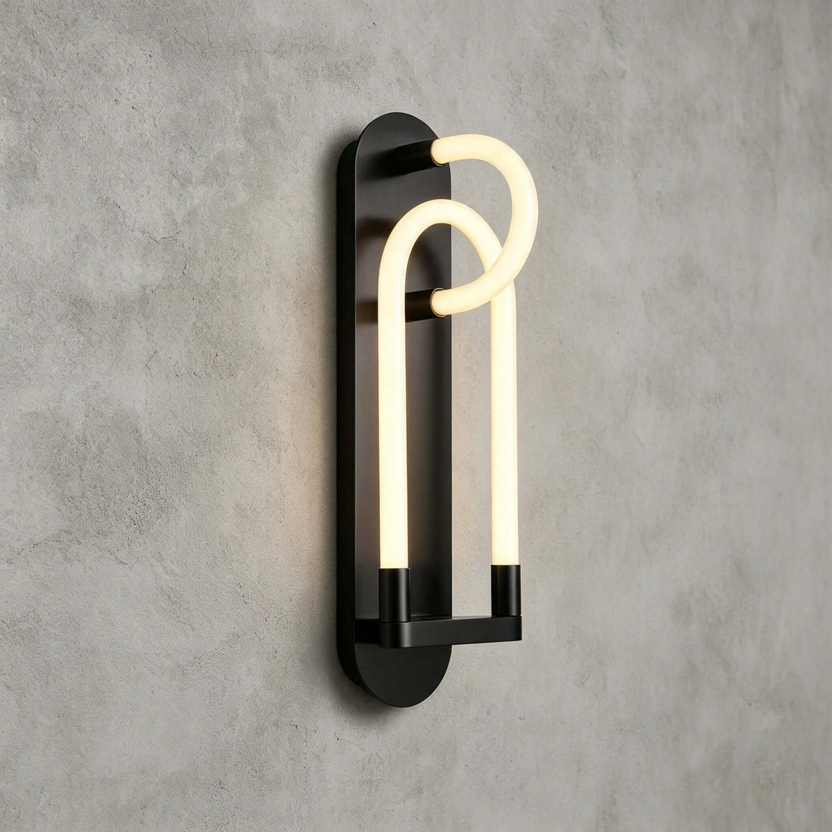 Black Clérachic wall light from an angle, its two nested glowing loops standing out from a long oval backplate.