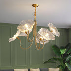 The Clérachic Lotus Blossom Chandelier's clear glass shades lit above a console in a green-panelled living room with a plant.