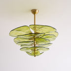 Green Clérachic Lotus Leaf Glass Chandelier seen from below, five tiers of glass leaves against a pale wall.