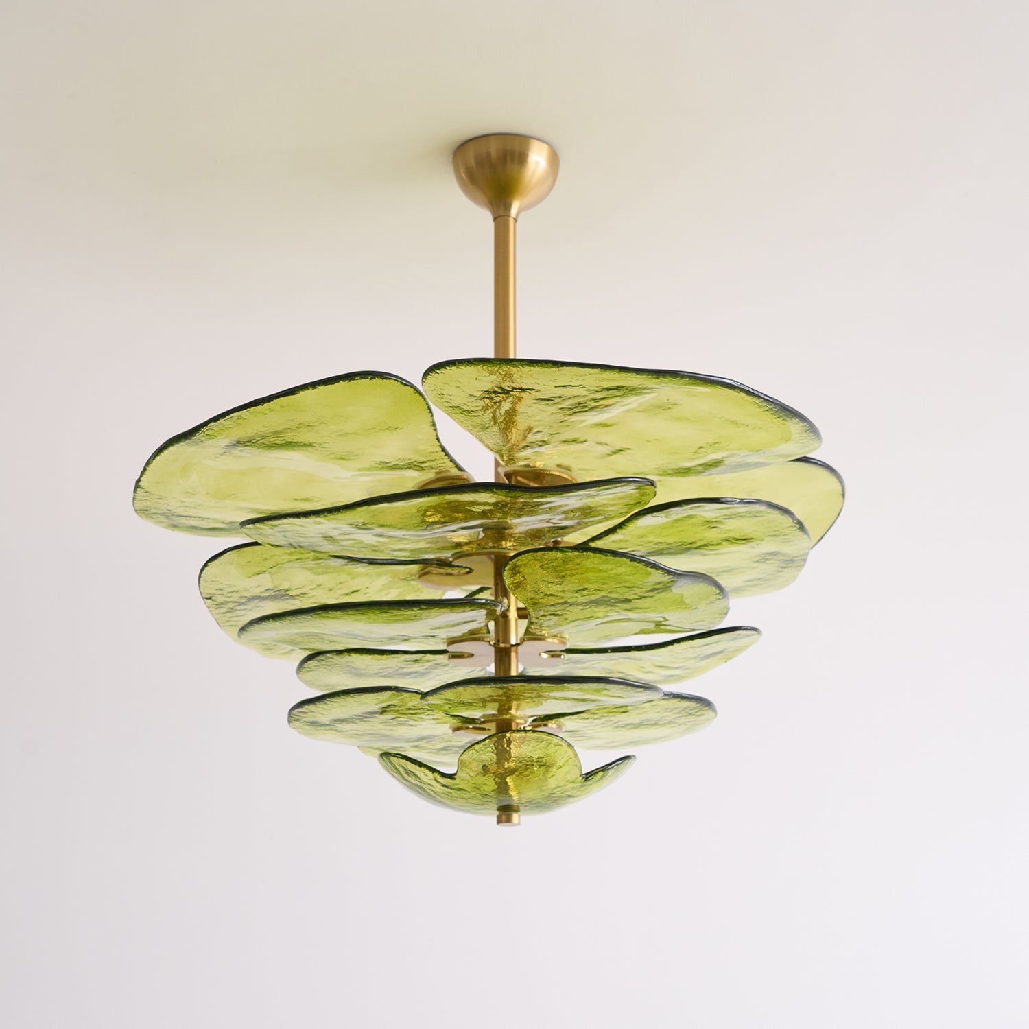 Green Clérachic Lotus Leaf Glass Chandelier seen from below, five tiers of glass leaves against a pale wall.
