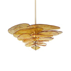 Amber Clérachic lotus leaf chandelier lit on white, the honey-gold glass glowing from the bulbs at its core.