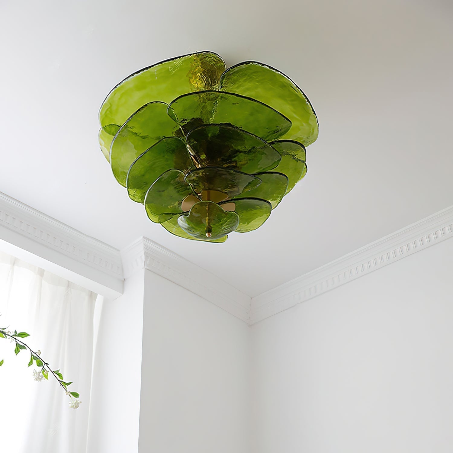 Green Clérachic lotus leaf chandelier unlit on a white ceiling, dark-rimmed leaves fanning over the cornice.
