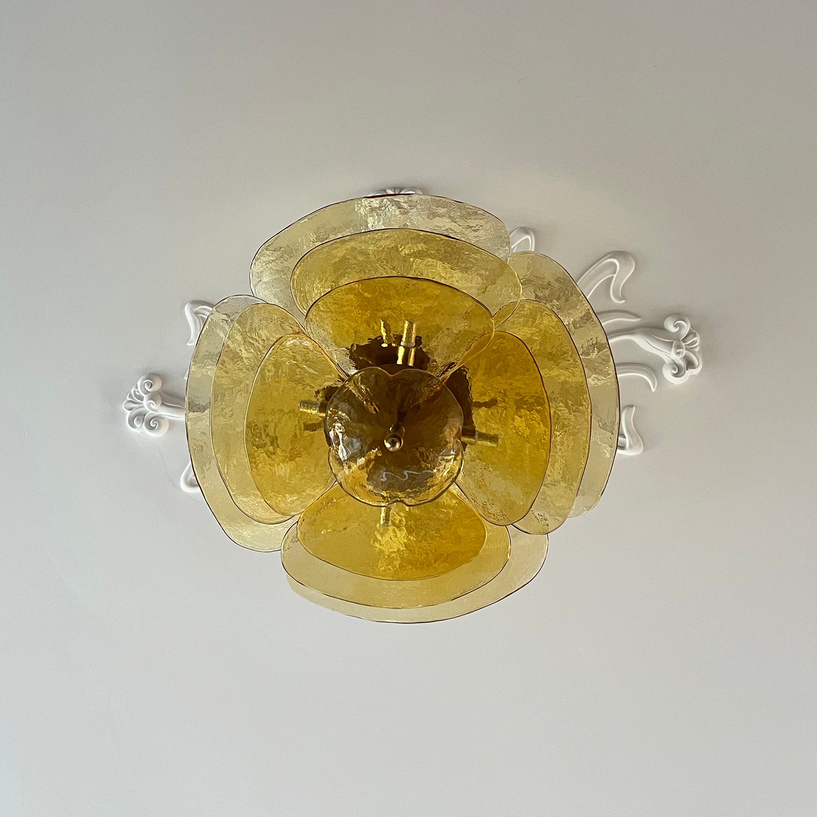 Amber Clérachic Lotus Leaf Glass Chandelier seen straight from below against a ceiling with plaster scrollwork.