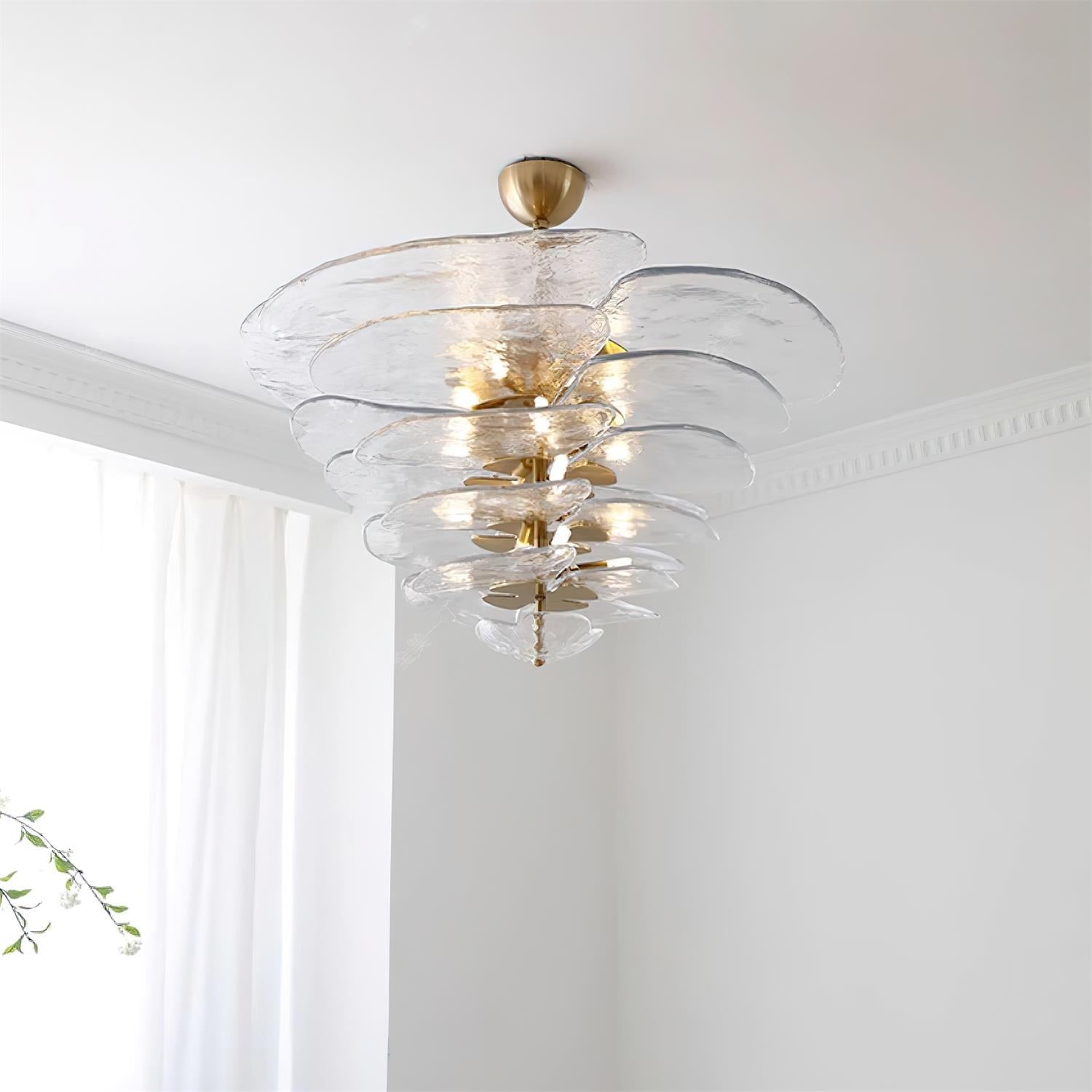 Clear Clérachic lotus leaf chandelier lit in a bright corner, light bouncing off the stacked transparent leaves.