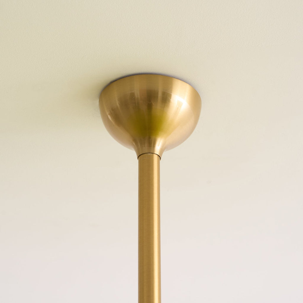 Detail of the brushed brass dome canopy and slim rod where the Clérachic chandelier meets the ceiling.
