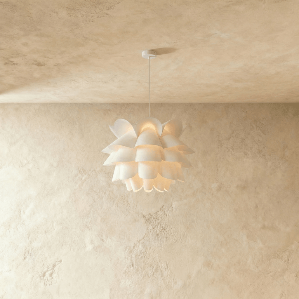 Clérachic white petal-layered pendant glowing warm on a slim white cord and canopy, against a limewashed wall.