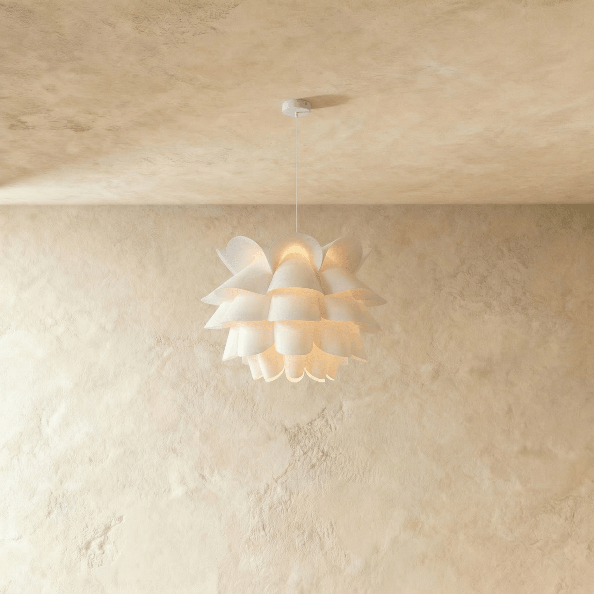 Clérachic white petal-layered pendant glowing warm on a slim white cord and canopy, against a limewashed wall.