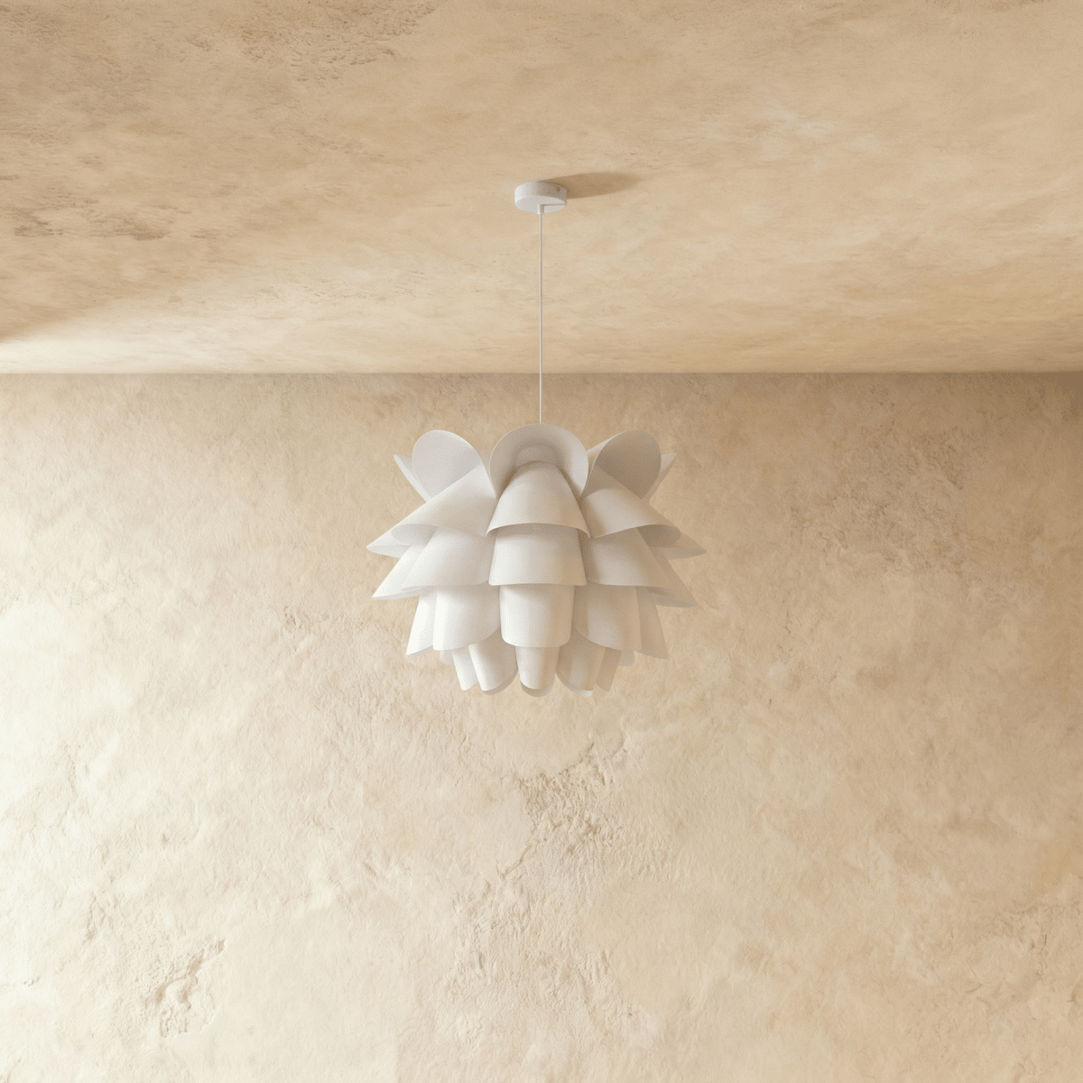 Clérachic white petal-layered pendant, unlit, hung from a thin white cord and round canopy on a plaster wall.