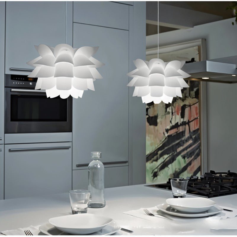 Two Clérachic white petal-layered pendants hung over a pale kitchen island set with plates, glasses and a water bottle.