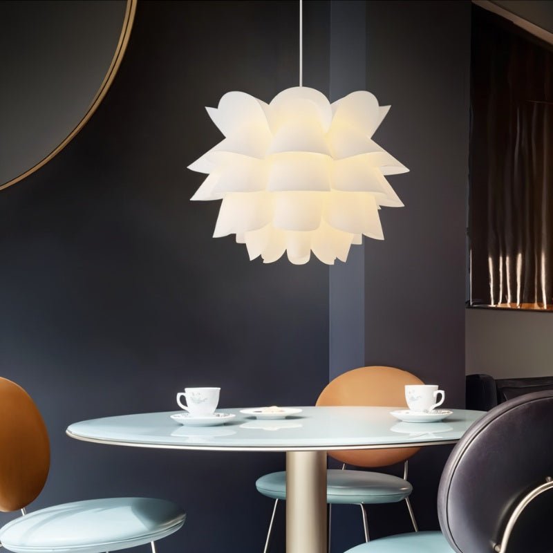 Clérachic white petal-layered pendant glowing above a round pale table with two cups, against a deep navy wall.