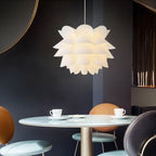 Clérachic white petal-layered pendant glowing above a round pale table with two cups, against a deep navy wall.