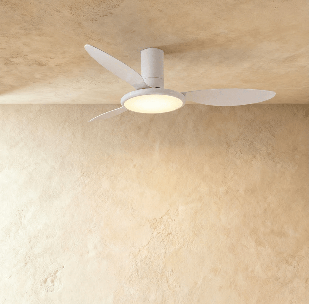 Clérachic matte white ceiling fan with a light: three slim blades and a round LED disc glowing warm under the motor, in studio.
