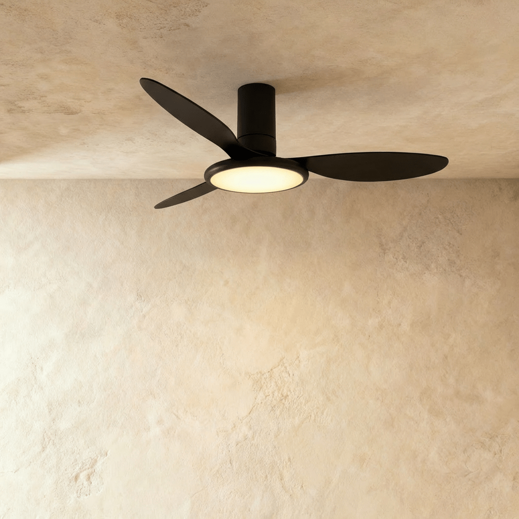 Clérachic matte black ceiling fan with a light, three slim black blades and a warm round LED disc under the motor, in studio.
