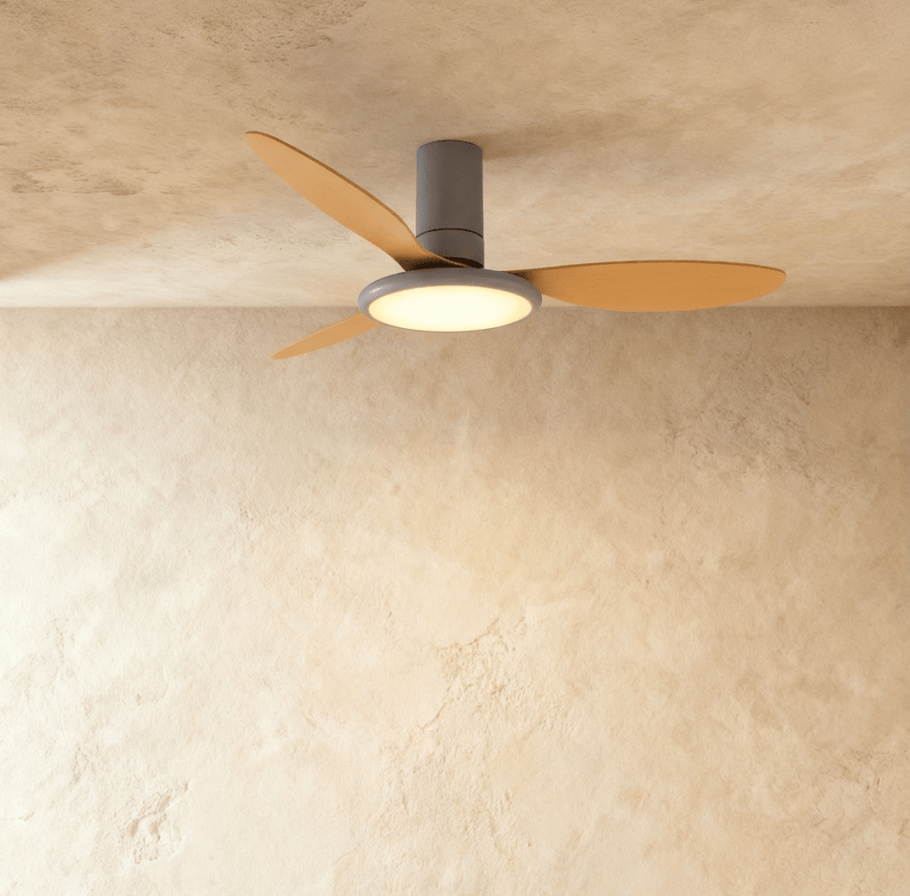 Clérachic ceiling fan with a light: a grey body with wood-toned blades and a glowing round LED disc, in a studio.