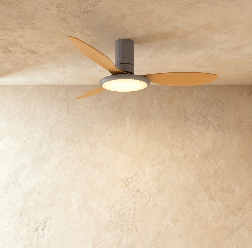 Clérachic ceiling fan with a light: a grey body with wood-toned blades and a glowing round LED disc, in a studio.