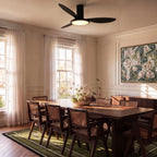 Clérachic matte black ceiling fan with a light over a long wooden dining table in a bright room with tall windows.