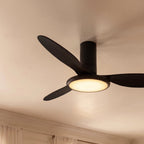Close up of the Clérachic matte black ceiling fan with a light, showing dark blades and a glowing round LED disc.