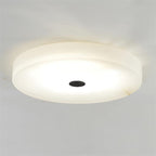 Lit close-up of the Clérachic flush mount ceiling light with the matte black cap, alabaster warming to cream across its underside.