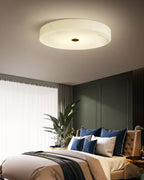 The Clérachic alabaster ceiling light above a green-panelled bedroom, sitting tight to the plaster with no rod or canopy on show.