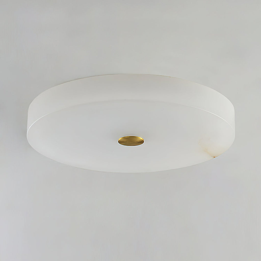 Unlit studio view of the Clérachic drum flush mount ceiling light, cool white stone with a polished brass disc at its centre.