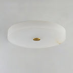 Unlit studio view of the Clérachic drum flush mount ceiling light, cool white stone with a polished brass disc at its centre.
