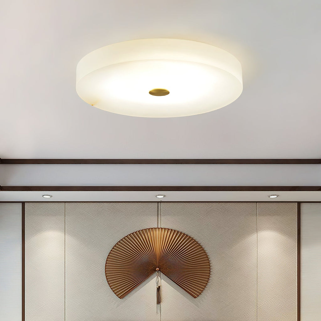 Clérachic drum flush mount ceiling light lit above a panelled wall, the alabaster disc reading as a plain lit circle from below.