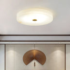 Clérachic drum flush mount ceiling light lit above a panelled wall, the alabaster disc reading as a plain lit circle from below.