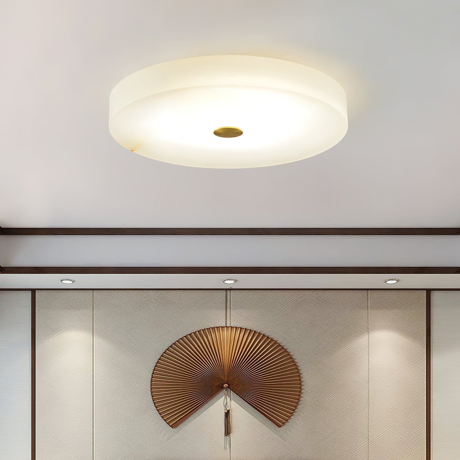 Clérachic drum flush mount ceiling light lit above a panelled wall, the alabaster disc reading as a plain lit circle from below.
