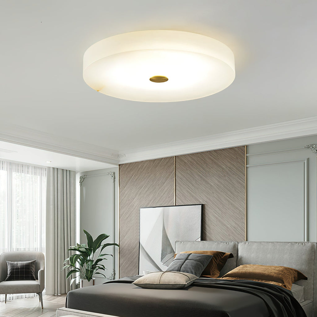 Clérachic flush mount ceiling light in a pale bedroom with cornice mouldings, glowing softly above the bed and leaning artwork.