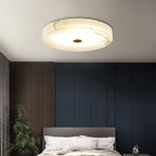 Clérachic alabaster ceiling light above a navy-panelled bedroom, warm veining tracing across the stone as it lights the room.