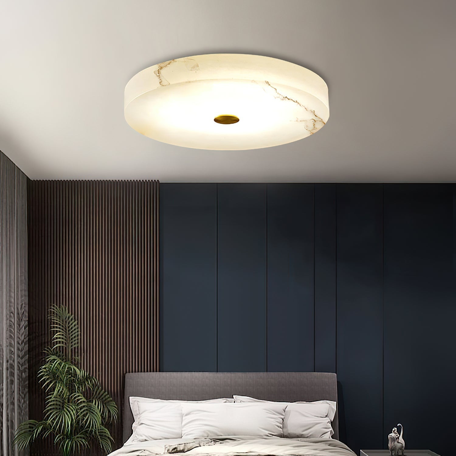 Clérachic alabaster ceiling light above a navy-panelled bedroom, warm veining tracing across the stone as it lights the room.