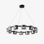 Black-frame ring chandelier from Clérachic with smoked glass shades around a circular band, hung on thin cables on a plain white backdrop.