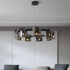 Close, lit view of a black-frame Clérachic chandelier with smoked glass shades over a grey panelled wall and dark sofa cushions.