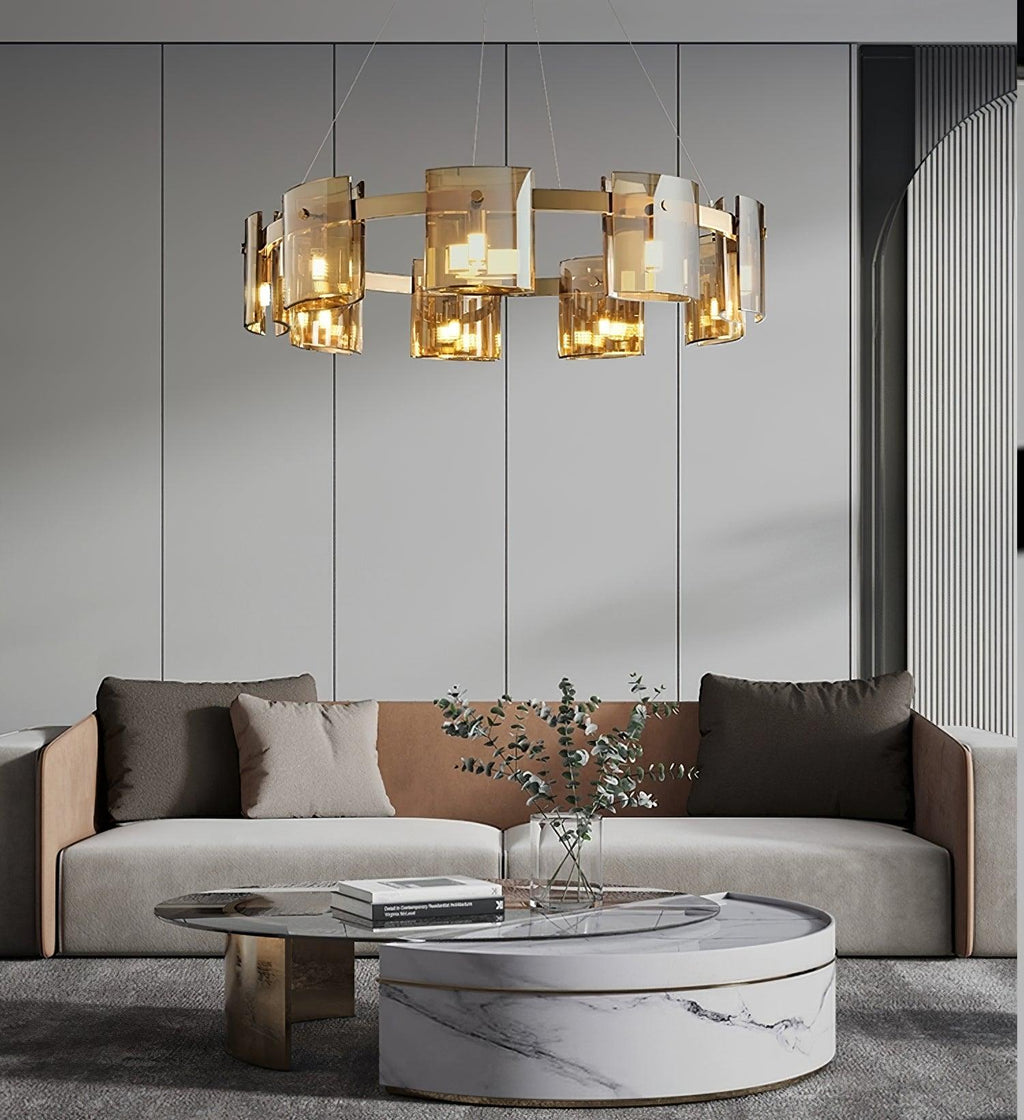 Gold-frame Clérachic chandelier with amber glass shades above a grey sofa and a round marble coffee table.