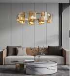 Gold-frame Clérachic chandelier with amber glass shades above a grey sofa and a round marble coffee table.
