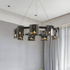 Black-frame Clérachic chandelier with smoked glass shades hung in a grey room beside long sheer curtains, seen from below.