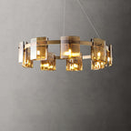 Gold-frame chandelier from Clérachic with amber glass shades lit, shown close on a grey backdrop with its thin hanging cables.