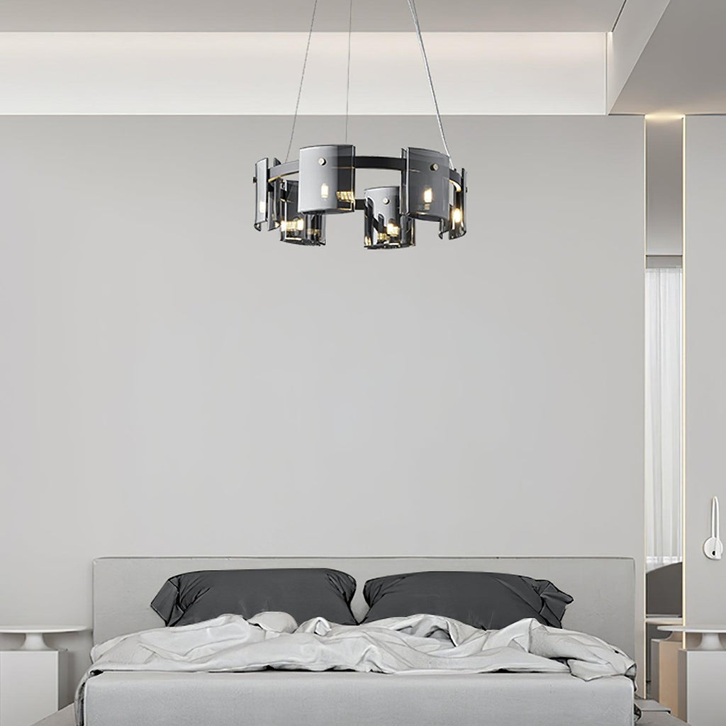 Black-frame Clérachic chandelier with smoked glass shades hung above a bed with grey pillows and white bedding.
